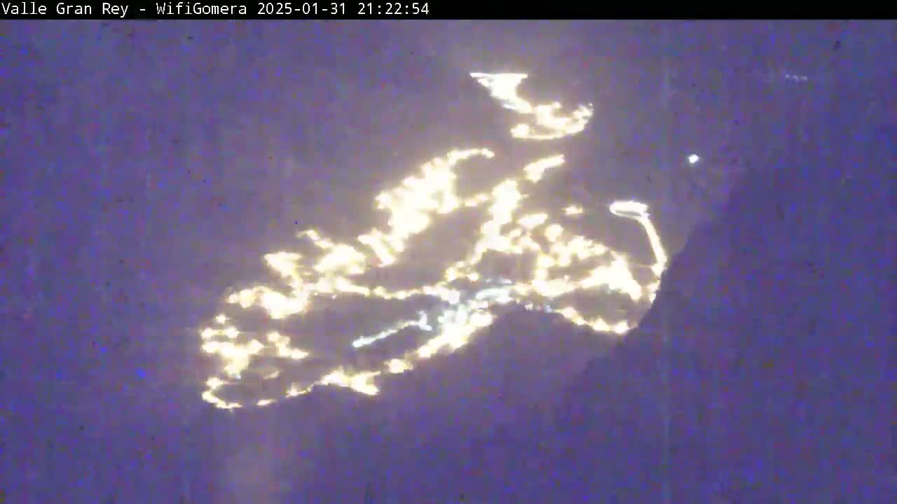 A nighttime image shows bright lights reflecting off of clouds or water in an irregular pattern.
