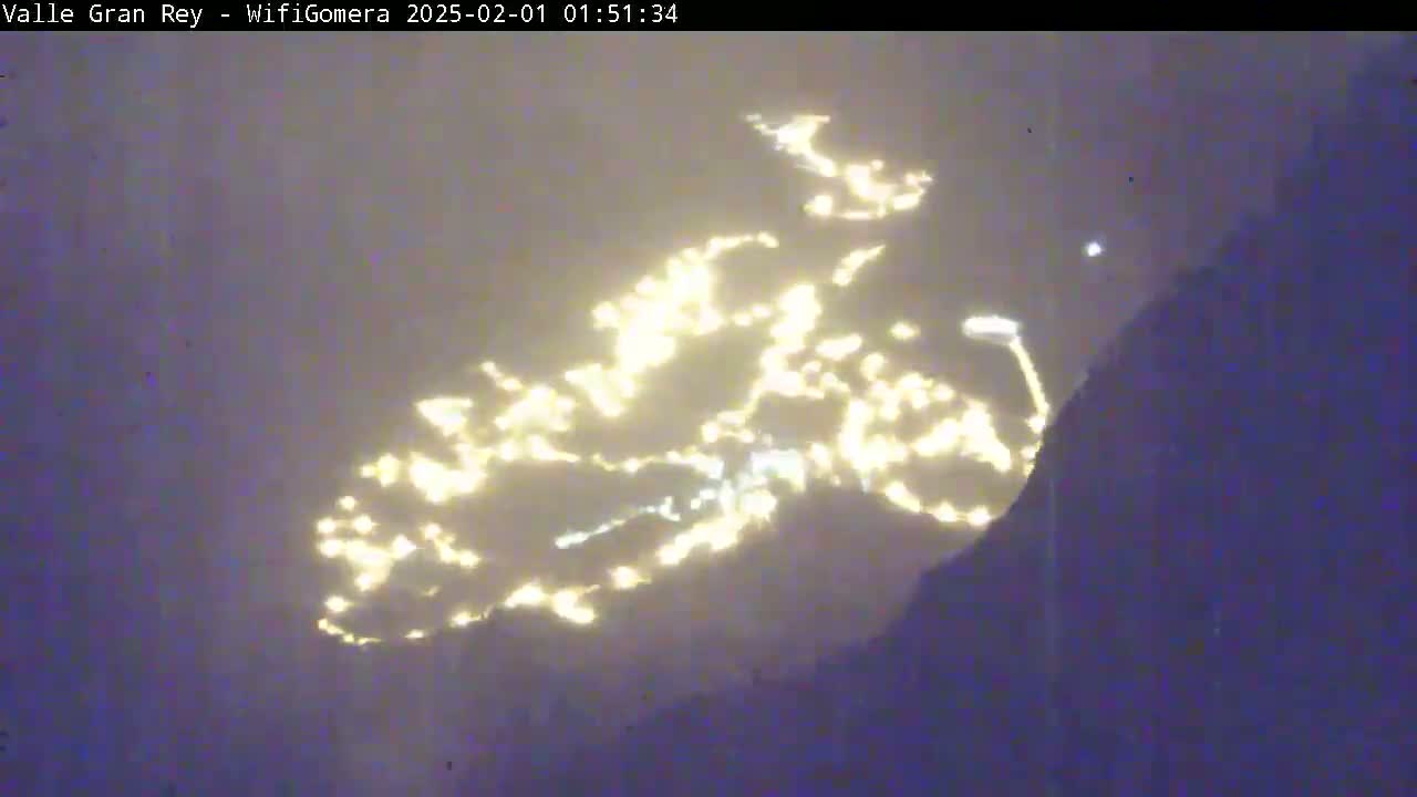 City lights are visible in the distance at night, partially obscured by a hazy atmosphere.