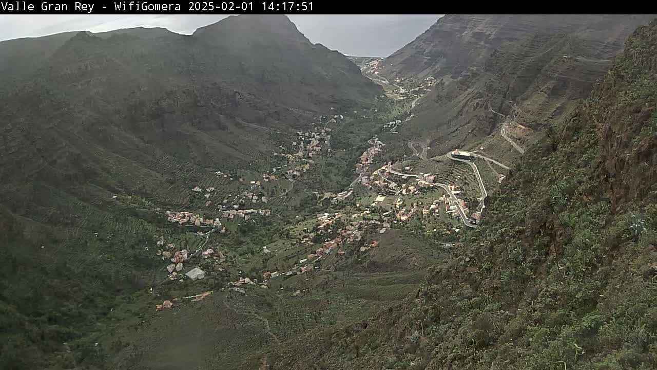 A mountainous valley town is seen on an overcast day, with winding roads snaking through the landscape.
