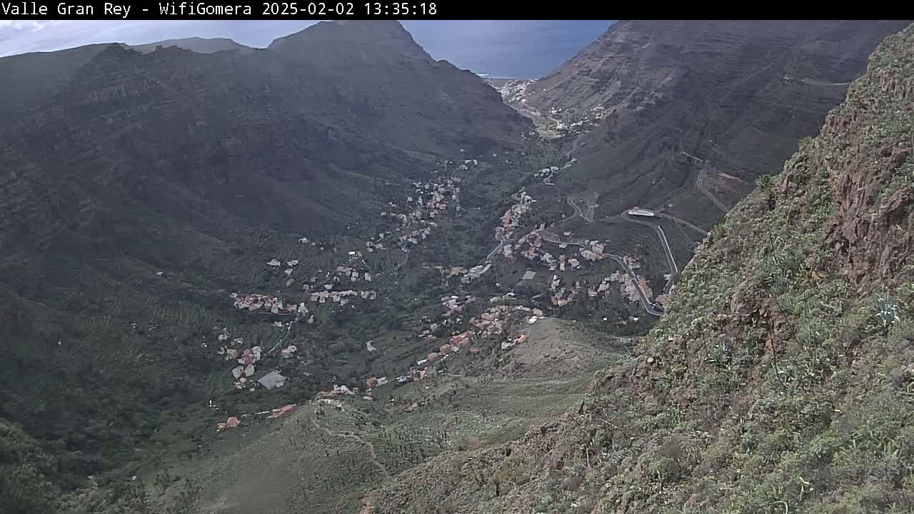 A mountainous valley village is seen from an elevated perspective on an overcast day.