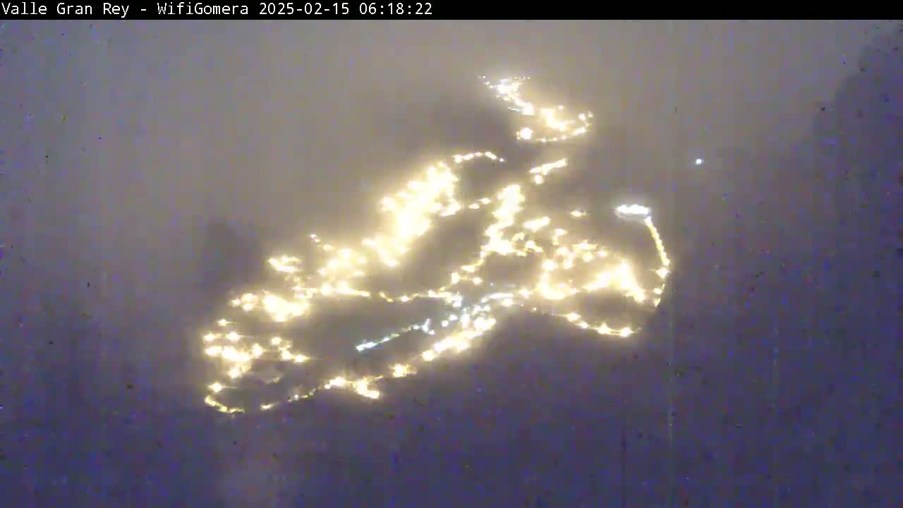 A hazy, dimly lit scene shows a scattering of small, bright lights in the distance, resembling city lights seen through fog or mist.