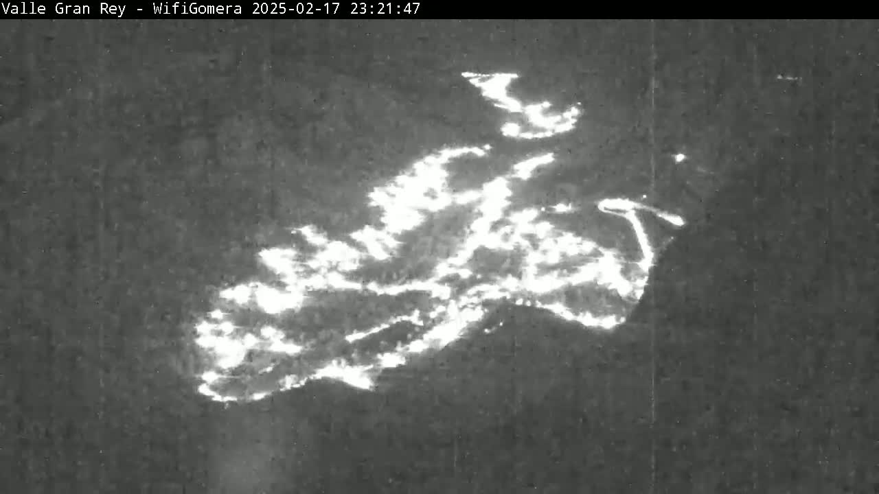 A nighttime, low-light image shows a large, irregularly shaped area of bright white light against a dark background.