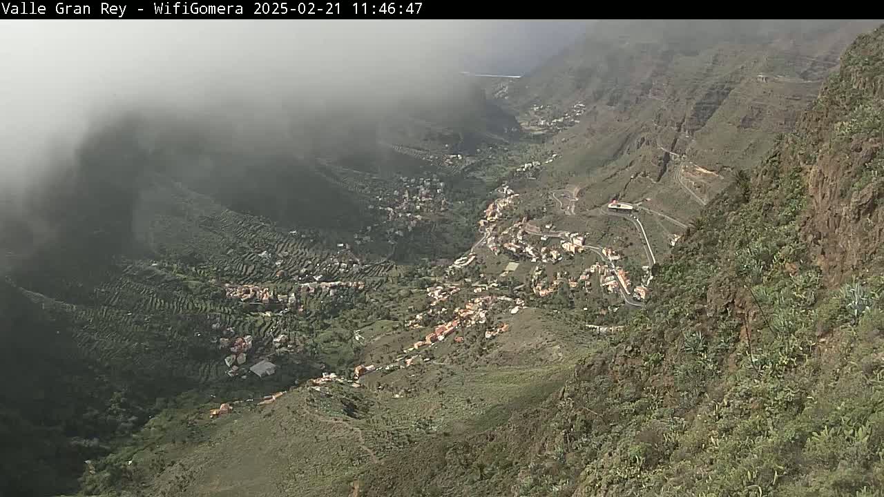 A misty mountain valley reveals a village nestled among terraced hillsides.