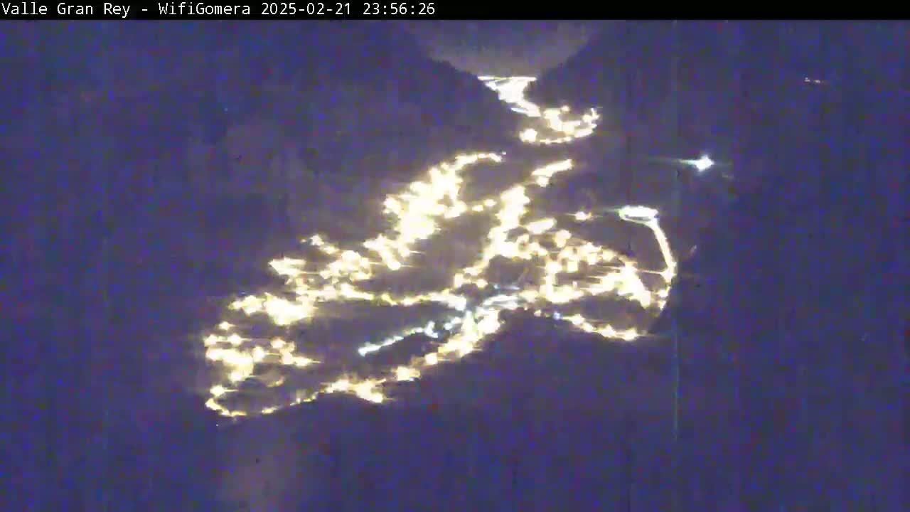 An aerial nighttime view shows a valley illuminated by numerous lights scattered across its landscape.