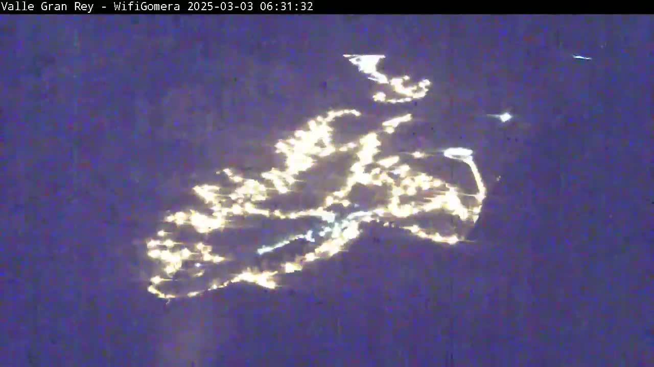An image shows a dark body of water reflecting light in an irregular, cloud-like pattern at night.