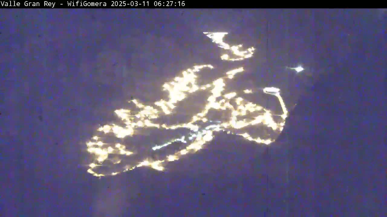 A nighttime image shows the reflection of city lights on a dark body of water.