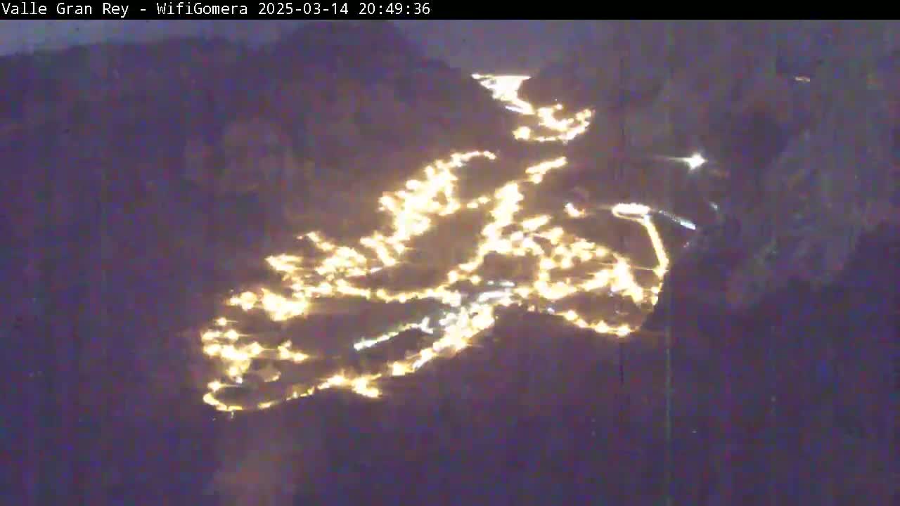 A nighttime, aerial view shows a town's lights scattered across a dark landscape.