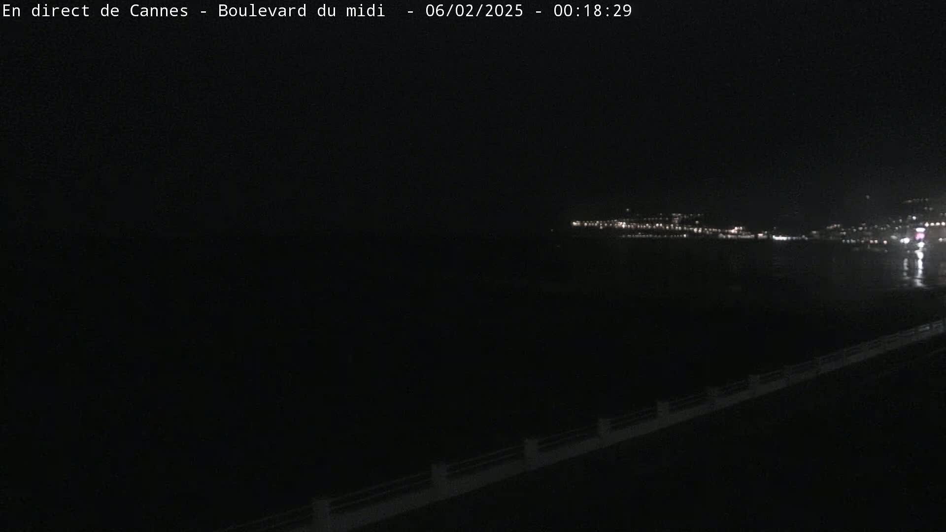 A nighttime, low-light view of a dark body of water with a distant city skyline illuminated by lights.