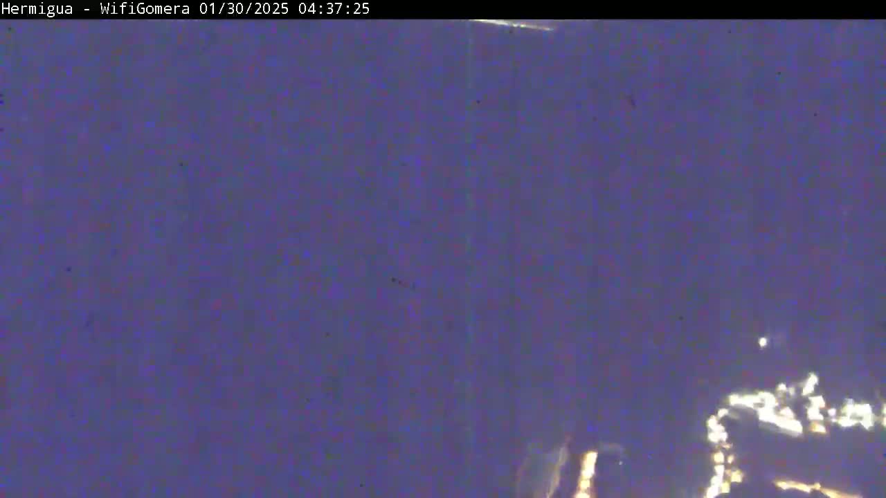 A dark, blurry nighttime scene shows a few faint lights in the distance.