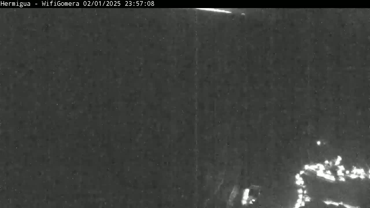 A nighttime, low-light image shows a dark, possibly overcast scene with faint lights visible in the lower right corner.