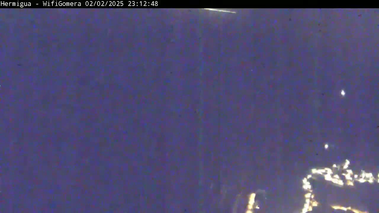 A night-time, long-range view shows a dark, blurry landscape with scattered points of light in the distance.
