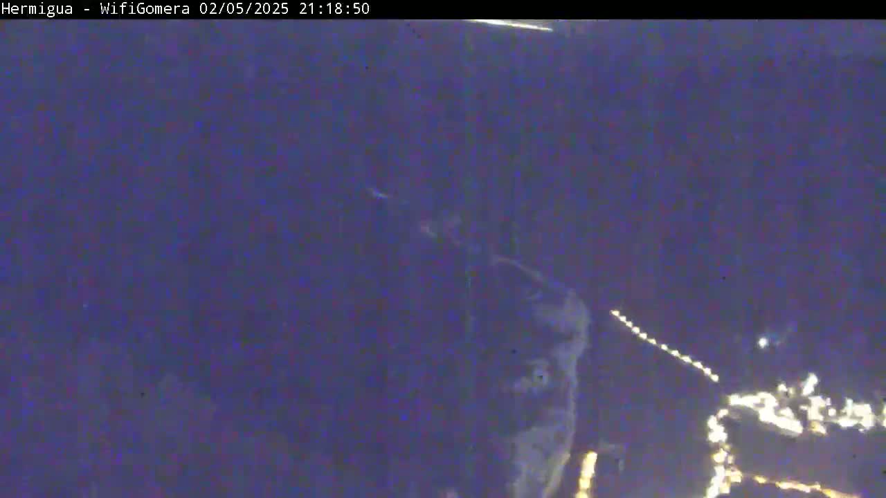 A blurry nighttime image shows a dark, possibly cloudy sky with faint lights visible in the distance.