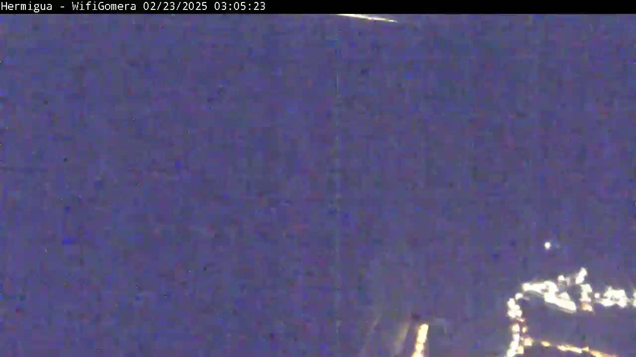 A blurry, dark purple image shows a nighttime scene with a few faint, bright lights in the bottom right corner.