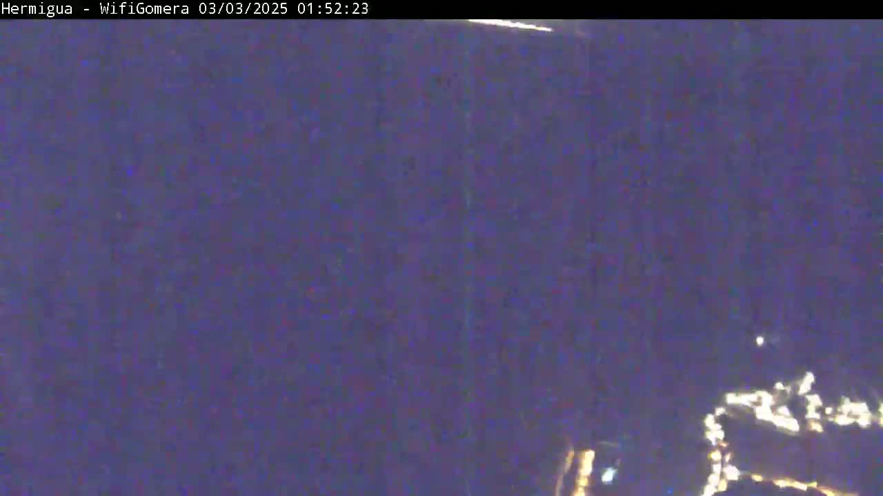A nighttime, blurry long shot shows a few faint lights in the distance under a dark sky.