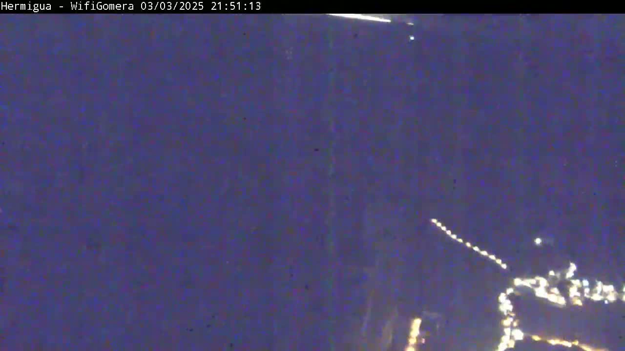 A nighttime, dark-purple view shows a string of lights in the distance, possibly a town or road at night.