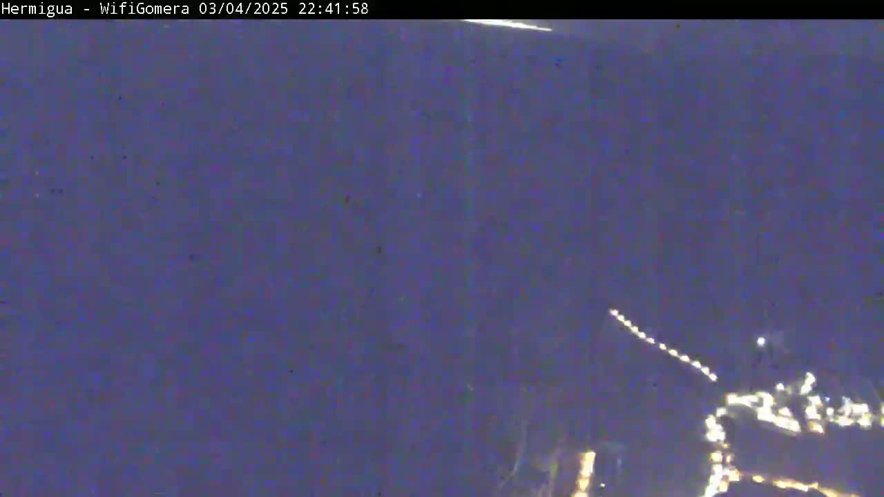 A nighttime long shot shows a blurry image of lights, possibly a city, against a dark, clear sky.