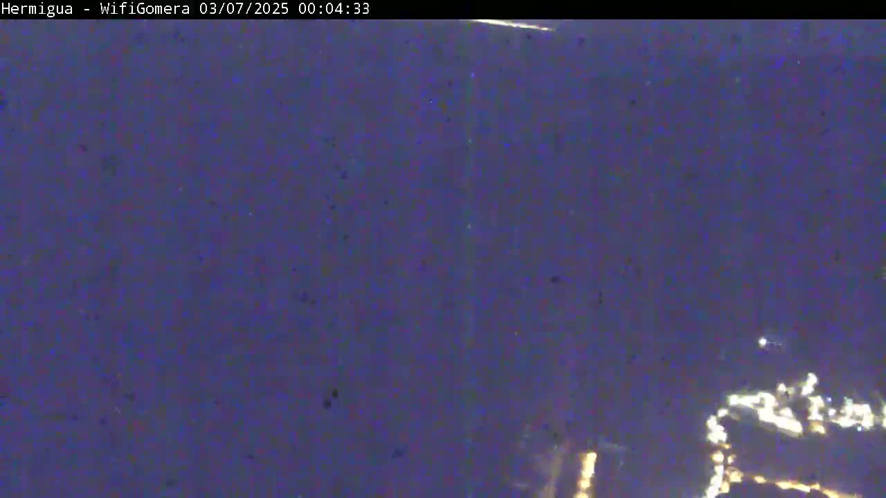 A low-light, blurry image shows a dark, possibly nighttime, scene with faint lights visible in the lower right corner.