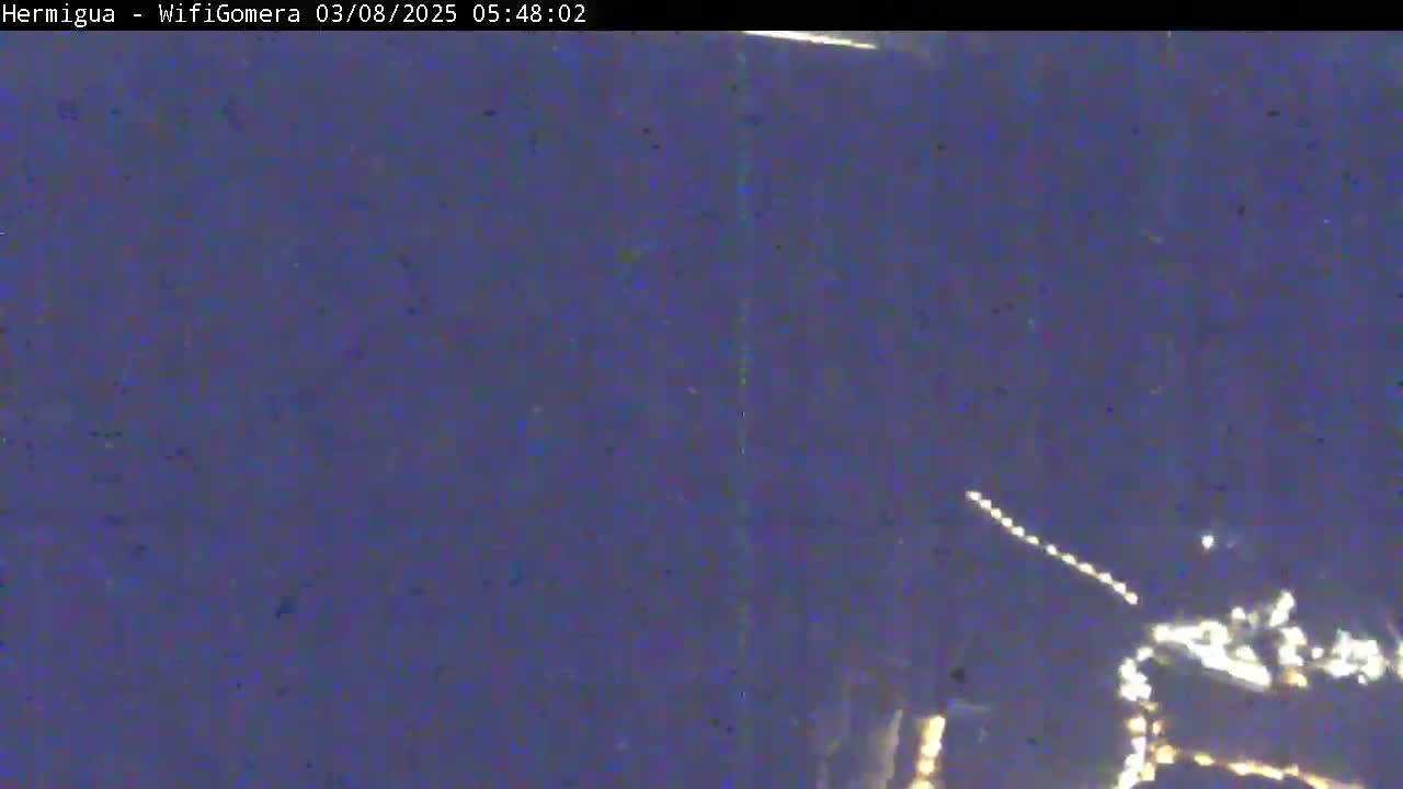 A nighttime, dark purple-blue sky shows distant, faint lights possibly from a town or city.