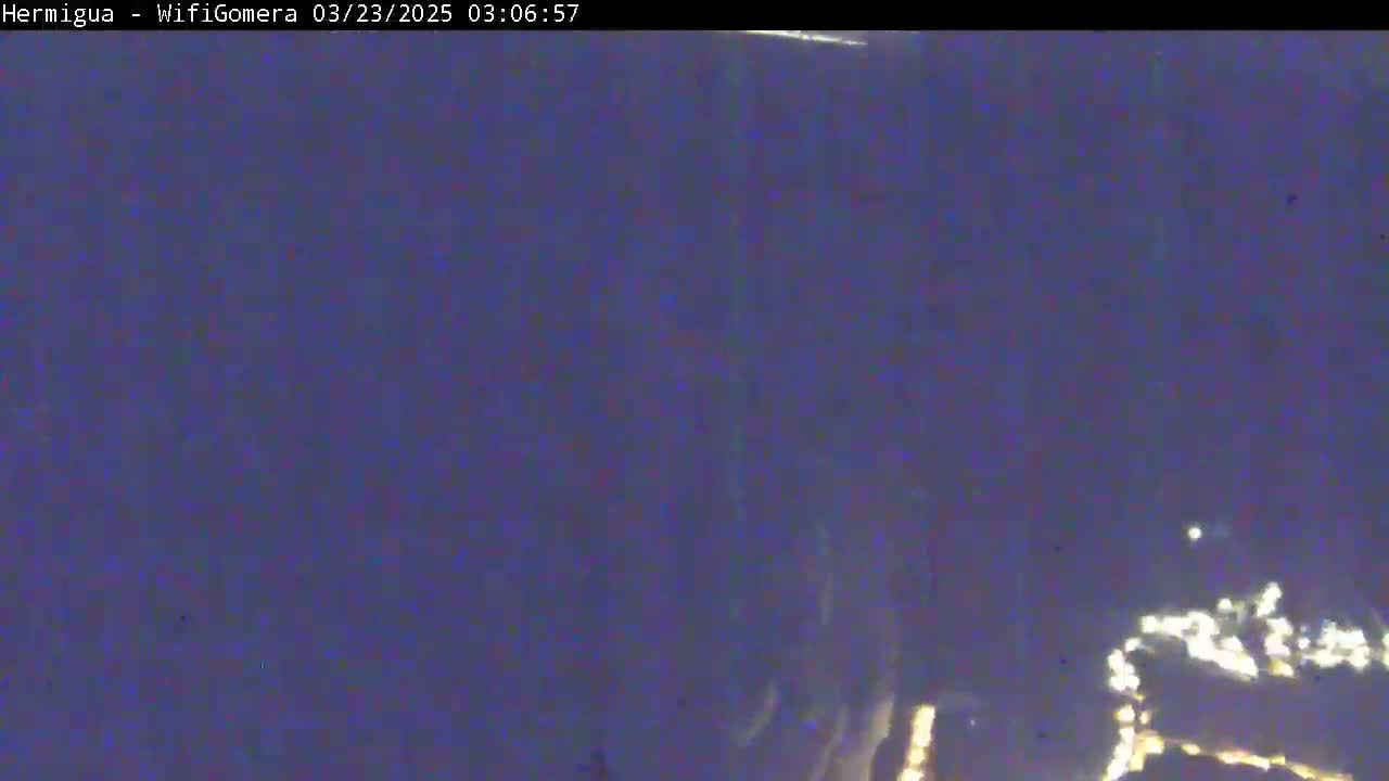 A nighttime, blurry view of distant, faint lights on a dark horizon.