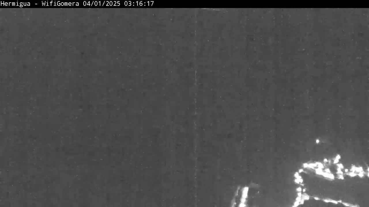 A grainy, low-light image shows a dark, possibly nighttime scene with indistinct shapes in the lower right corner that may be vehicles or objects.