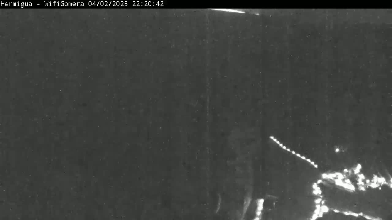 A nighttime, low-light image shows a dark scene with a few faint, bright lights in the lower right corner.