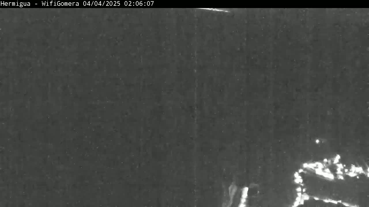 A low-light nighttime image shows a dark, possibly overcast, scene with faint lights visible in the bottom right corner.