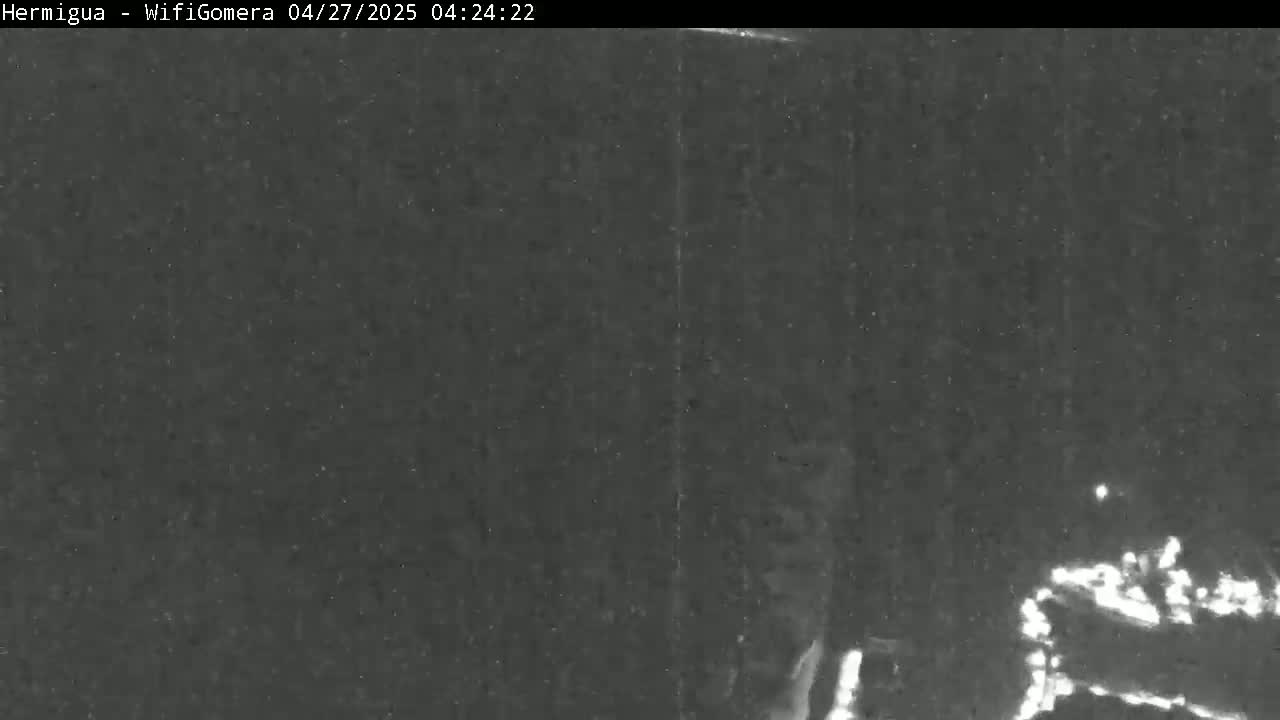 A low-light, nighttime image shows a dark, possibly grainy, scene with a few faint, bright spots in the lower right corner.