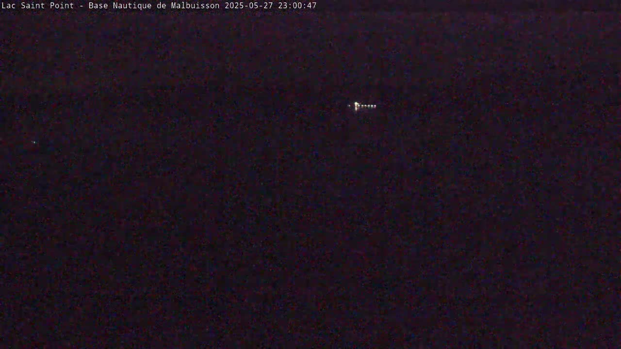 A dark, nighttime scene shows a distant line of lights on the water.