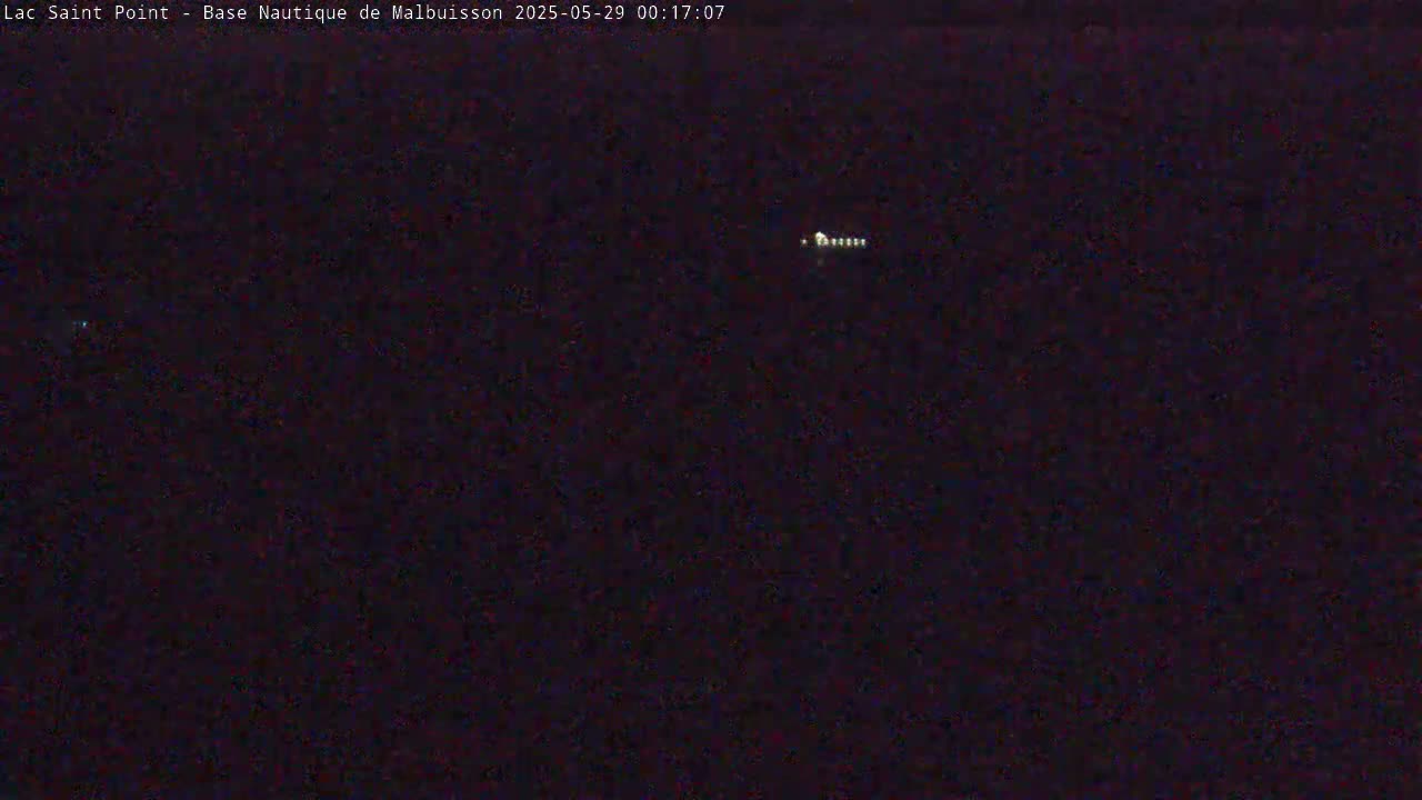 A dark, nighttime scene shows a faint line of lights in the distance.