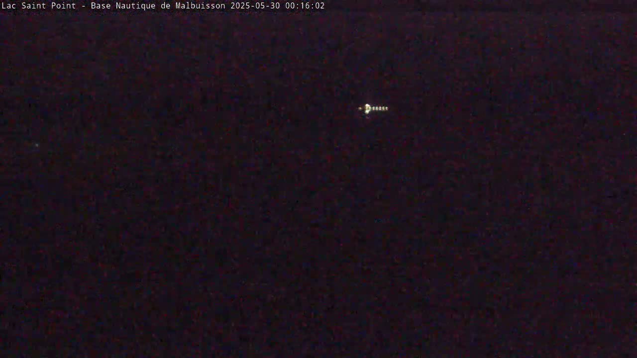 A small, bright light appears in a dark, nighttime sky.