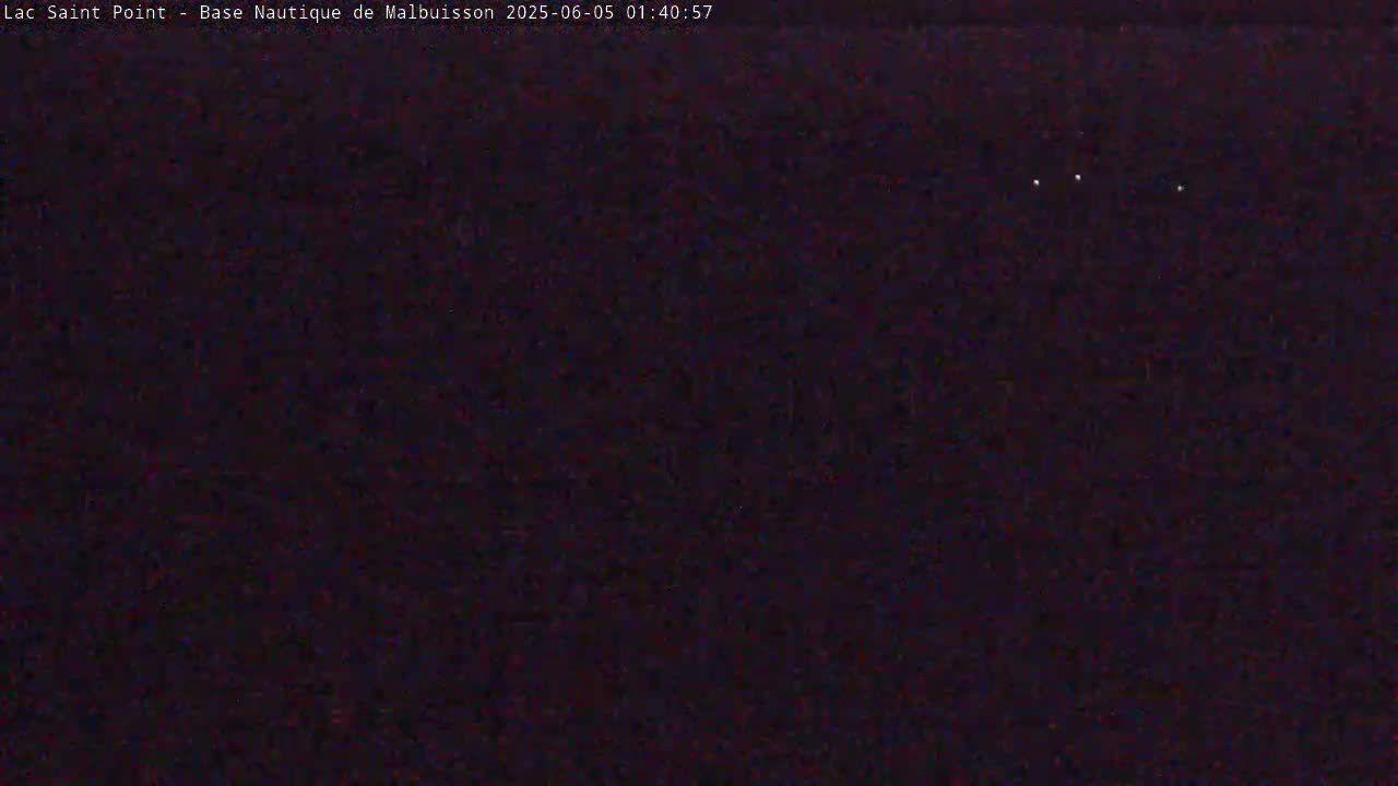 The image shows a dark, nighttime scene with a few small, bright lights visible in the distance.