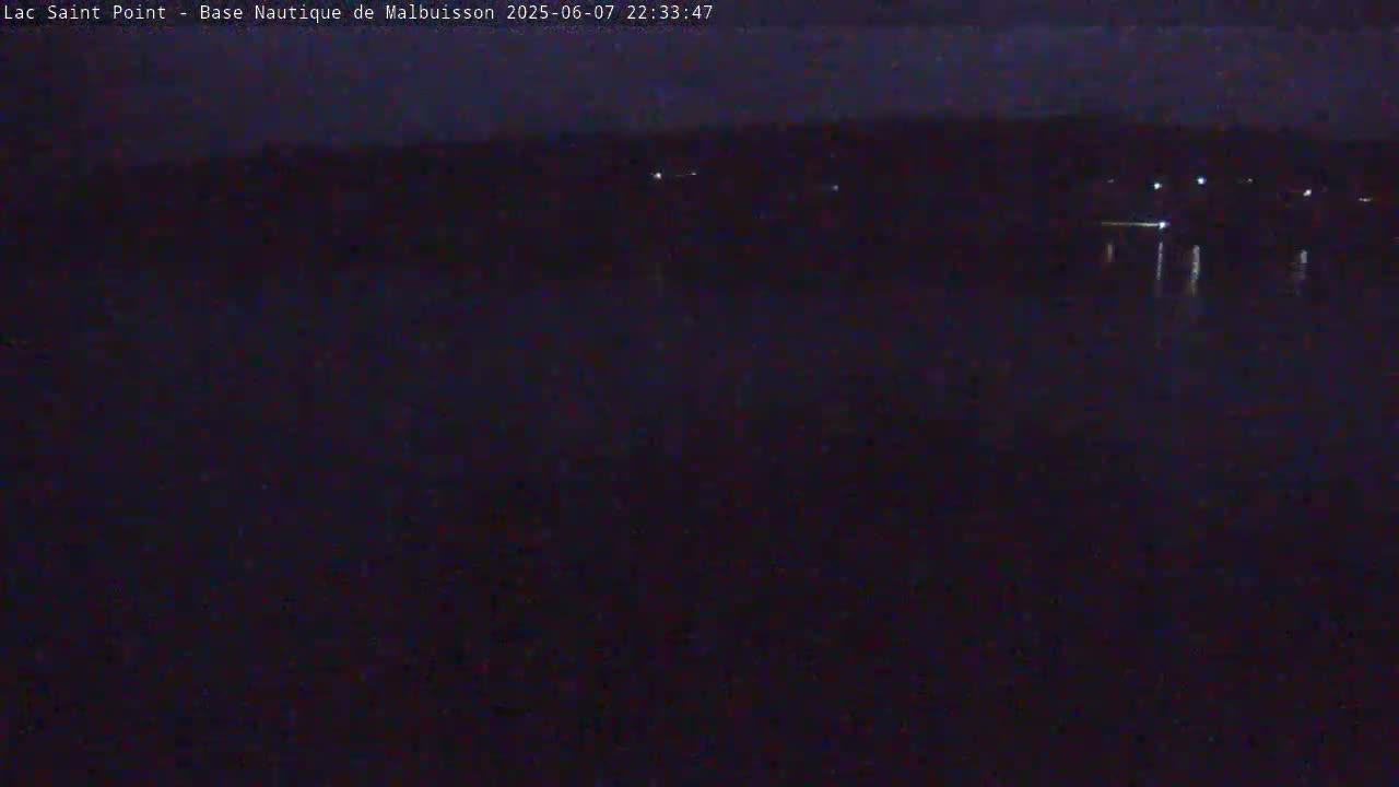 A dark, nighttime view of a body of water with faint lights visible on the far shore.