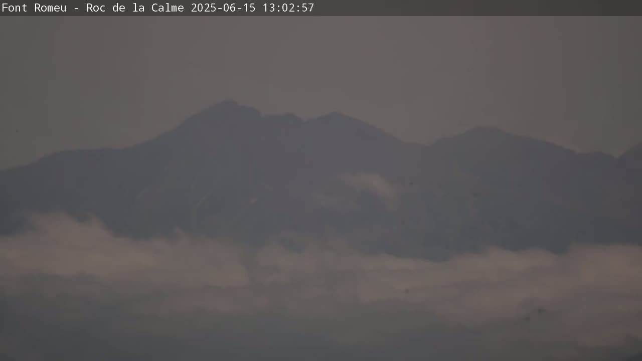 A hazy, mountainous landscape is partially obscured by low-lying clouds.