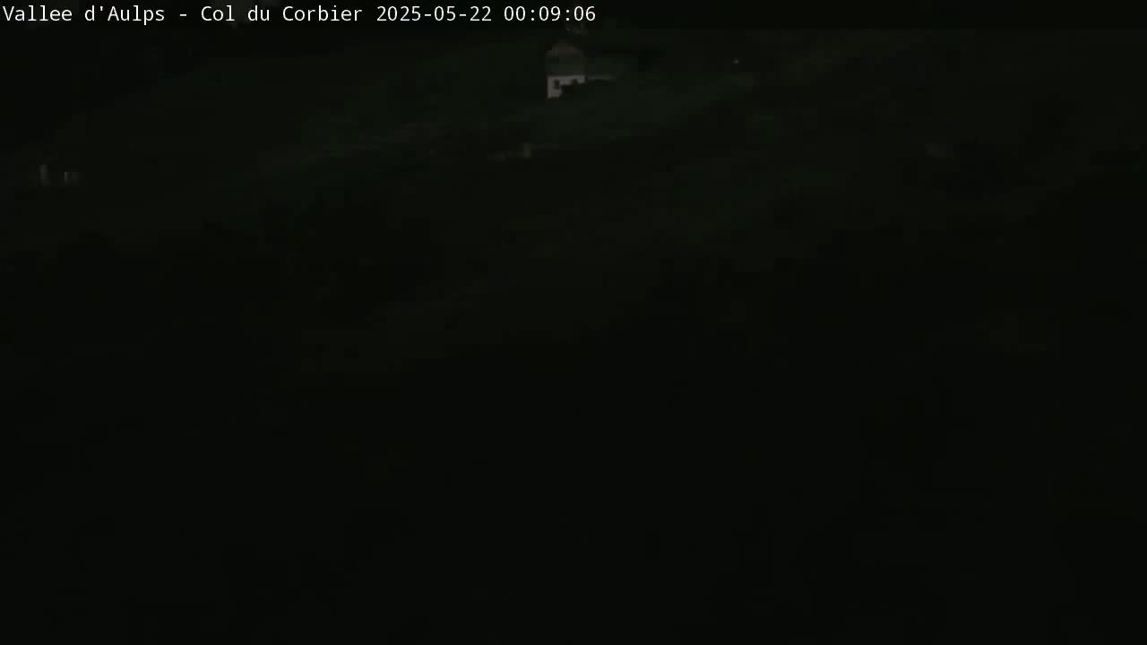 A very dark, nighttime outdoor scene is visible, with only faint light sources discernible in the distance.