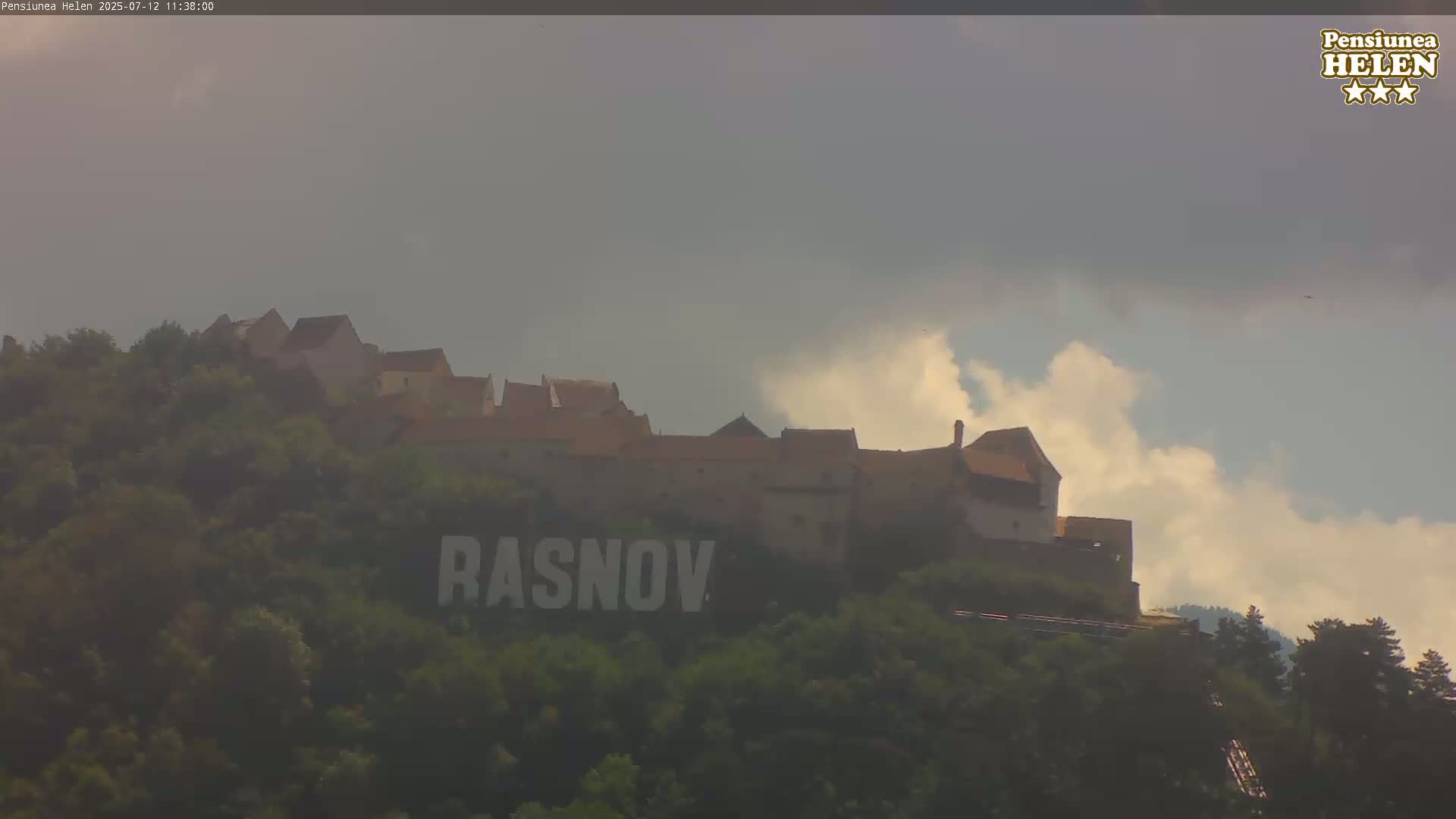 A hilltop castle is partially obscured by hazy, cloudy weather.