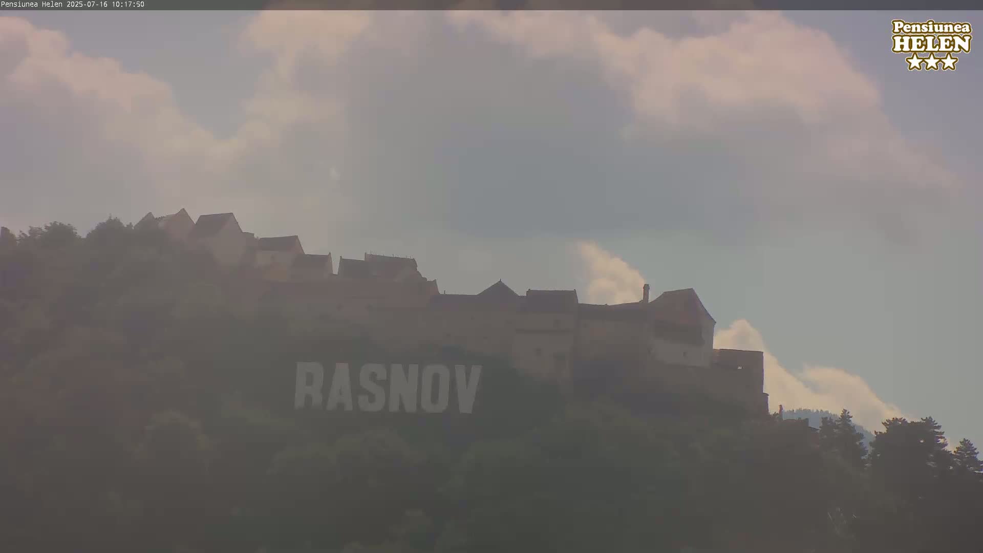 A castle sits atop a hill under a partly cloudy sky.