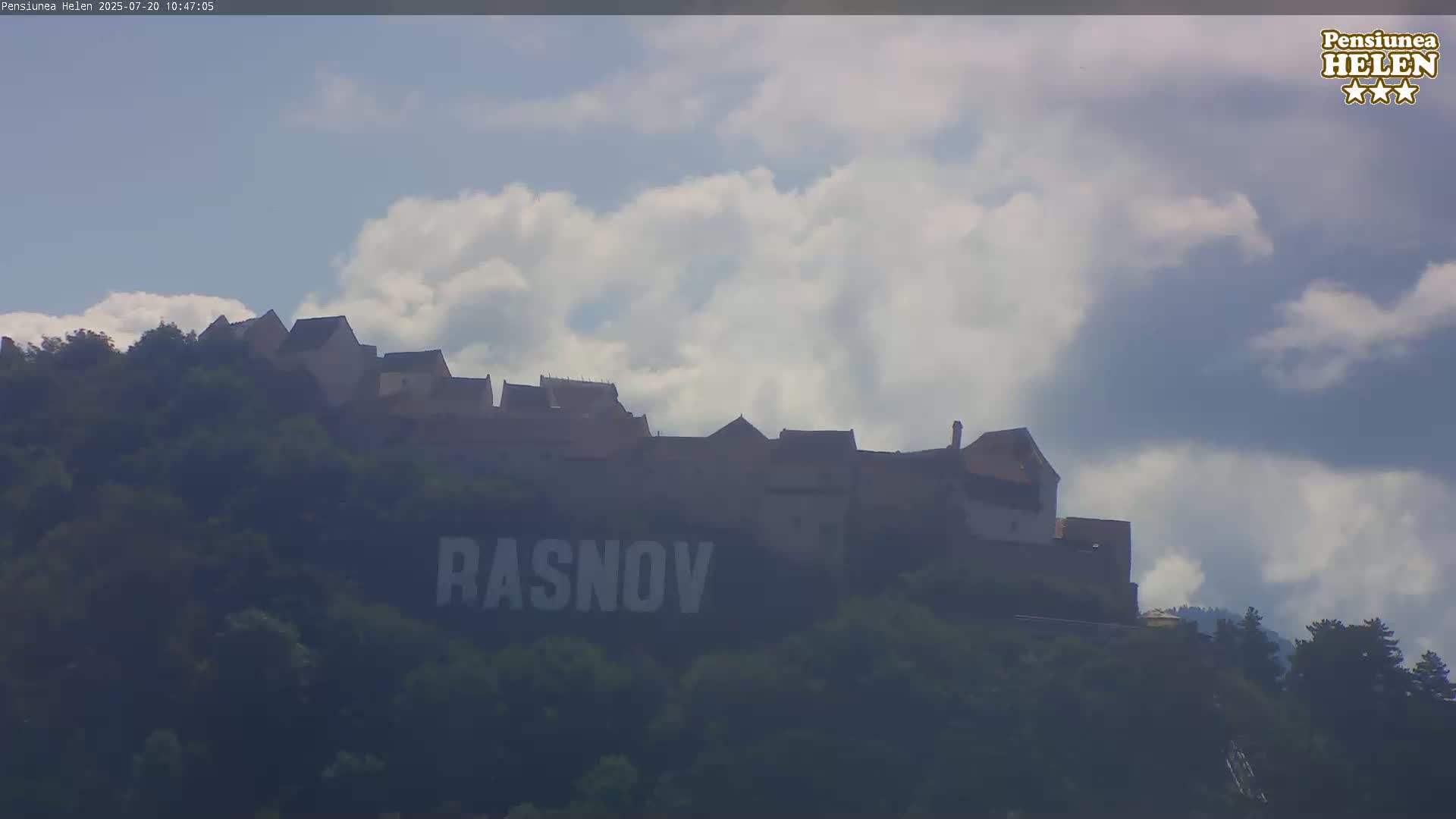 A castle sits atop a hill under a partly cloudy sky.