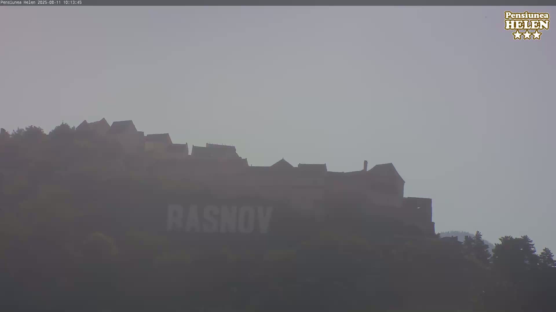 A hazy view shows a castle silhouetted on a hill, with the word "RASNOV" visible on the hillside below.