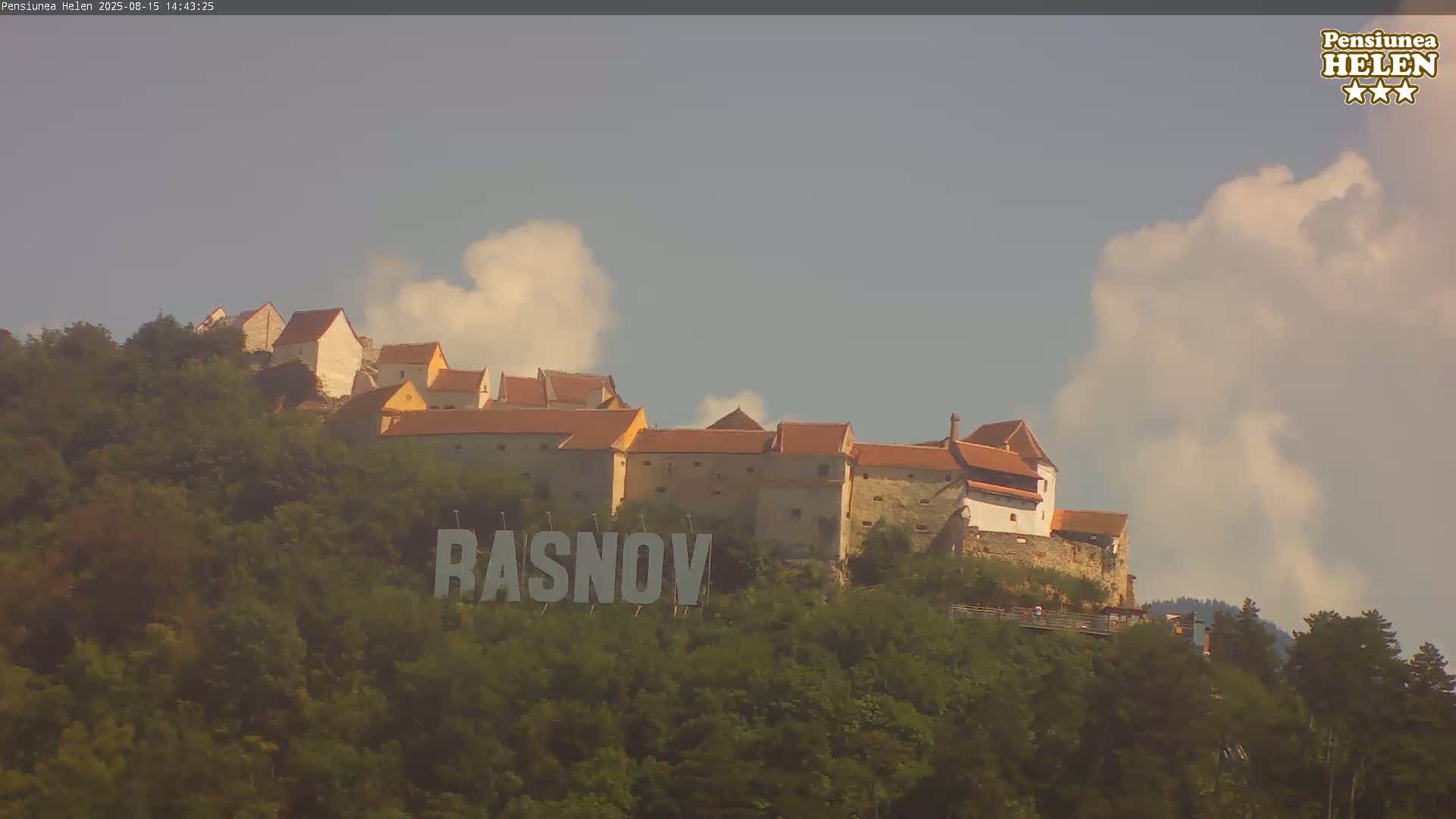 A hazy view shows a castle silhouetted on a hill, with the word "RASNOV" visible on the hillside below.