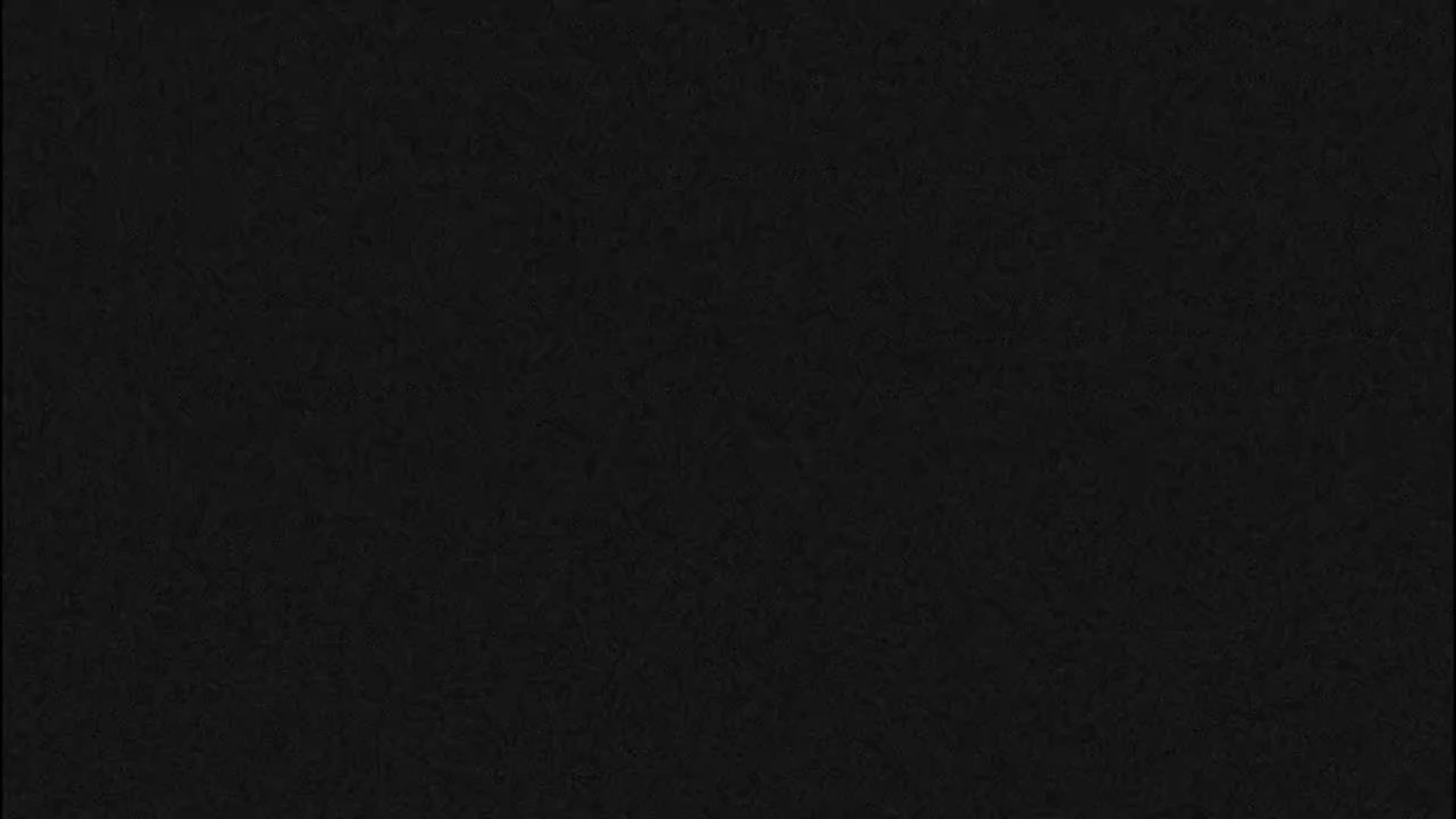 The image displays a solid black background with a subtle, dark grey textured or granular appearance.