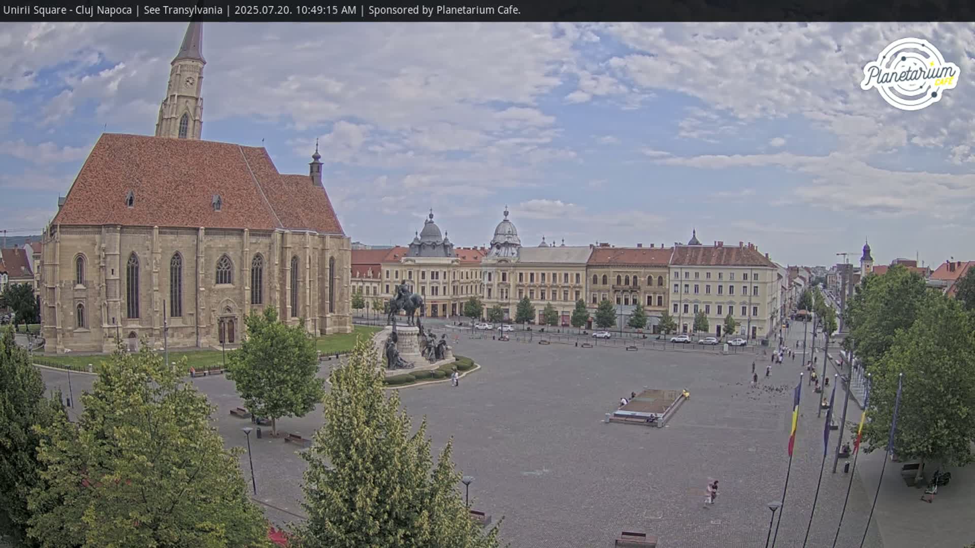 A large town square with a church and several buildings, under a partly cloudy sky.