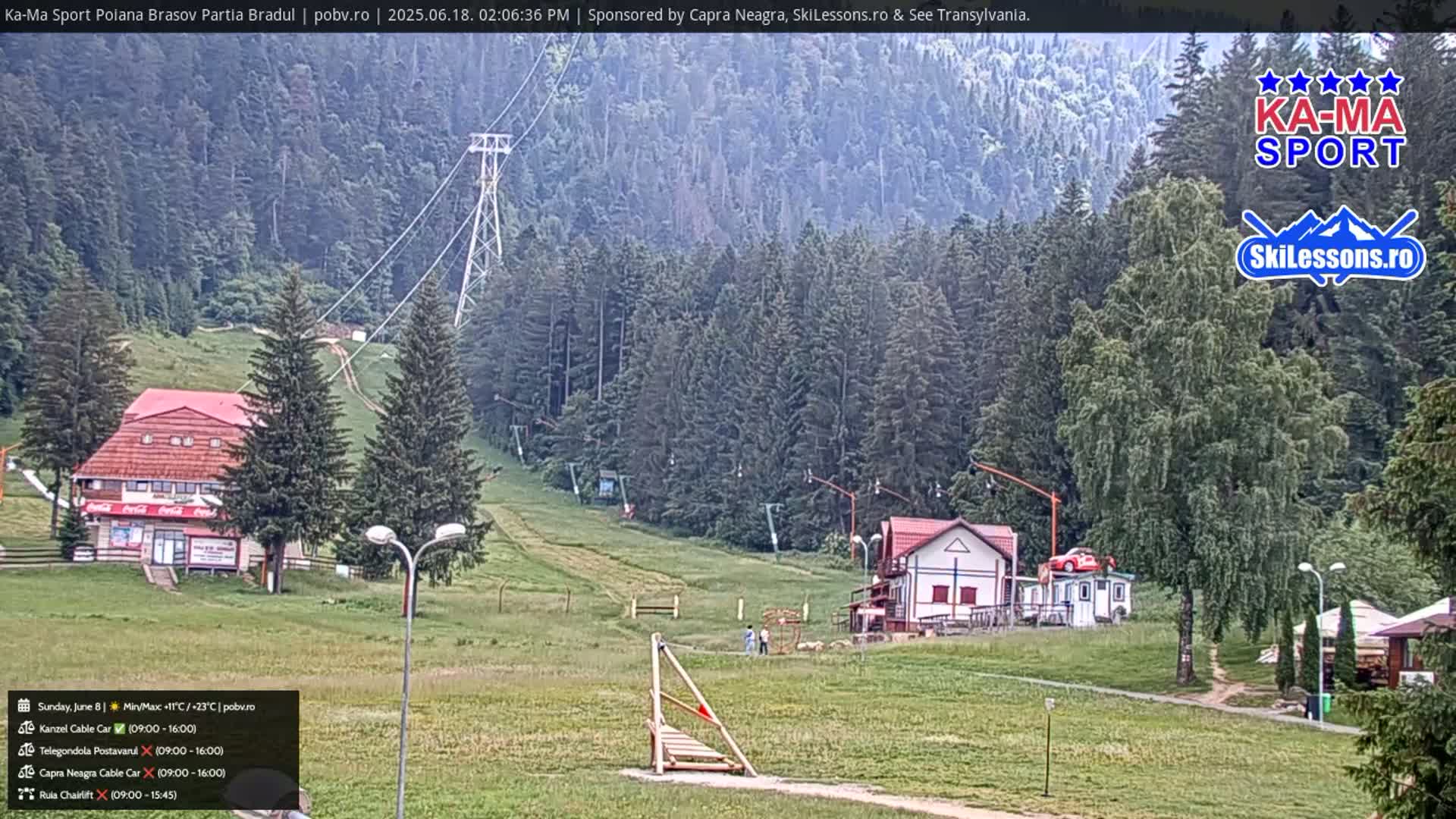 A ski resort in a mountainous area on an overcast day shows a chairlift, buildings, and grassy slopes.