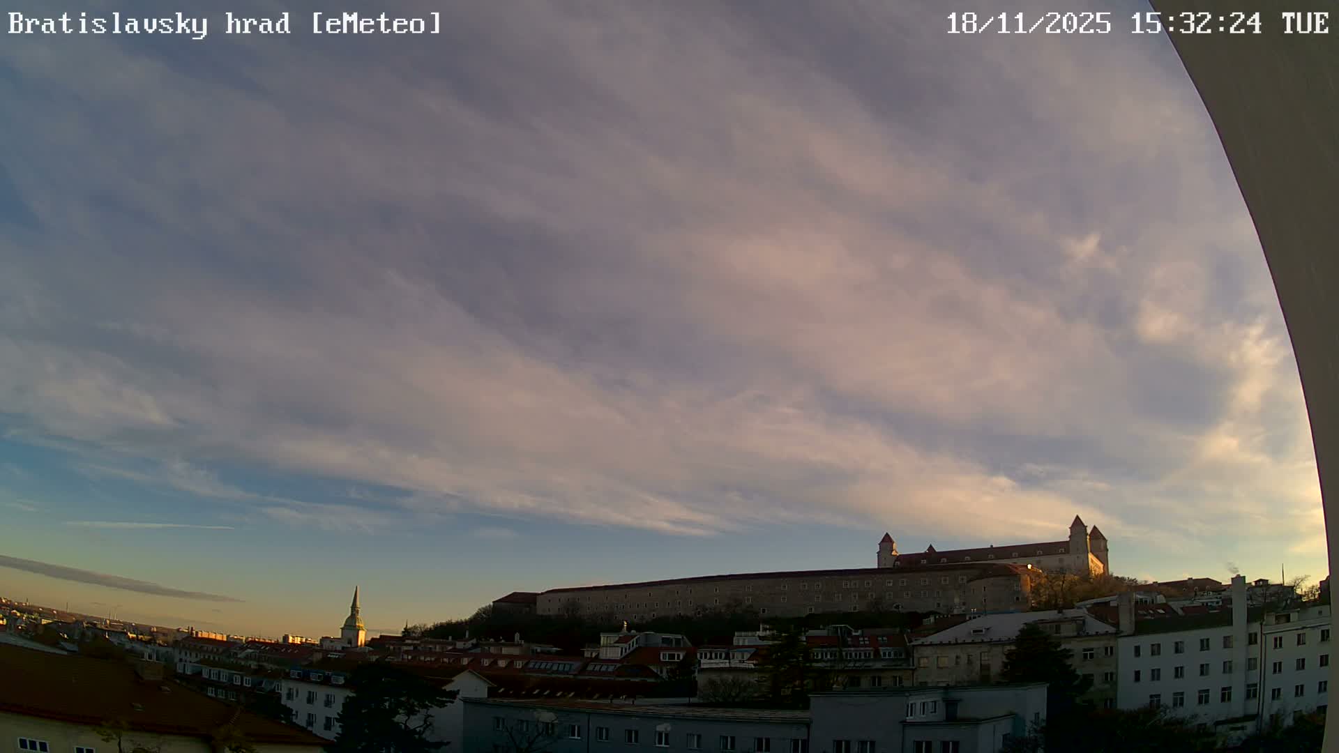 A nighttime, dark view shows dimly lit buildings and a dark sky.