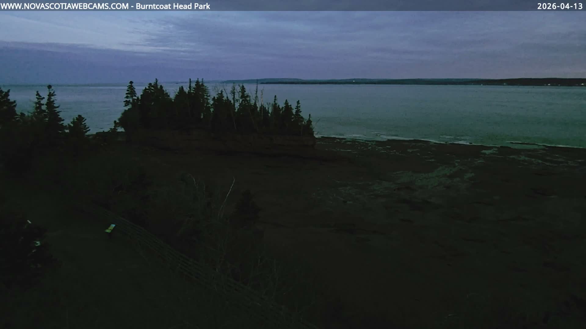 The image displays a very dark and indistinct outdoor scene at night, suggesting heavy overcast conditions or fog, with a few extremely faint distant lights barely visible in the upper right.
