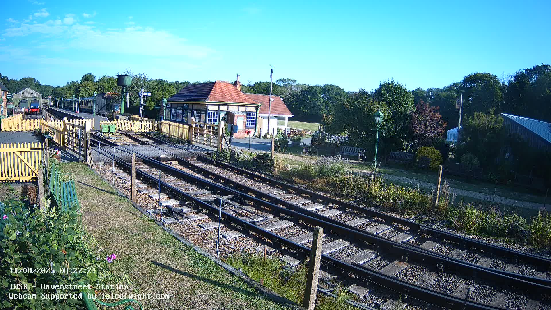 A train station with a train visible in the distance on a sunny day.