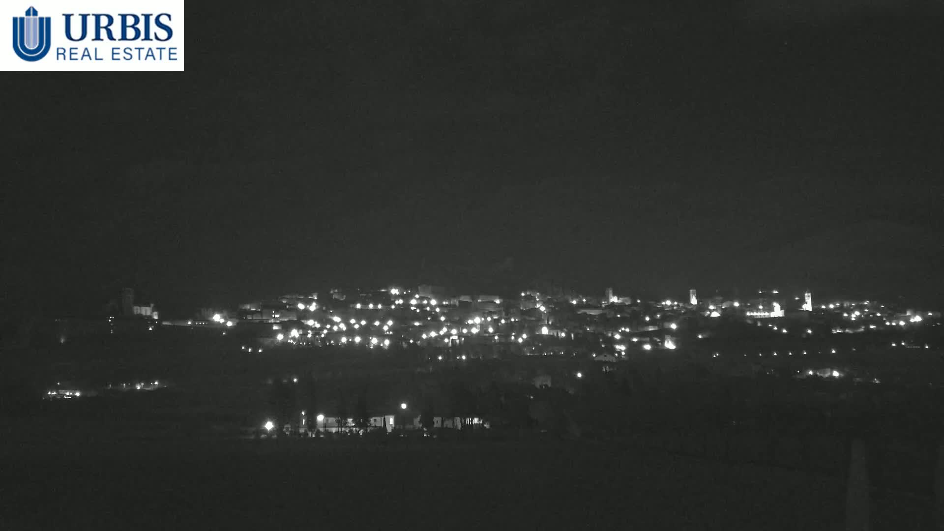 A nighttime long shot shows a town illuminated by many small lights against a dark sky.