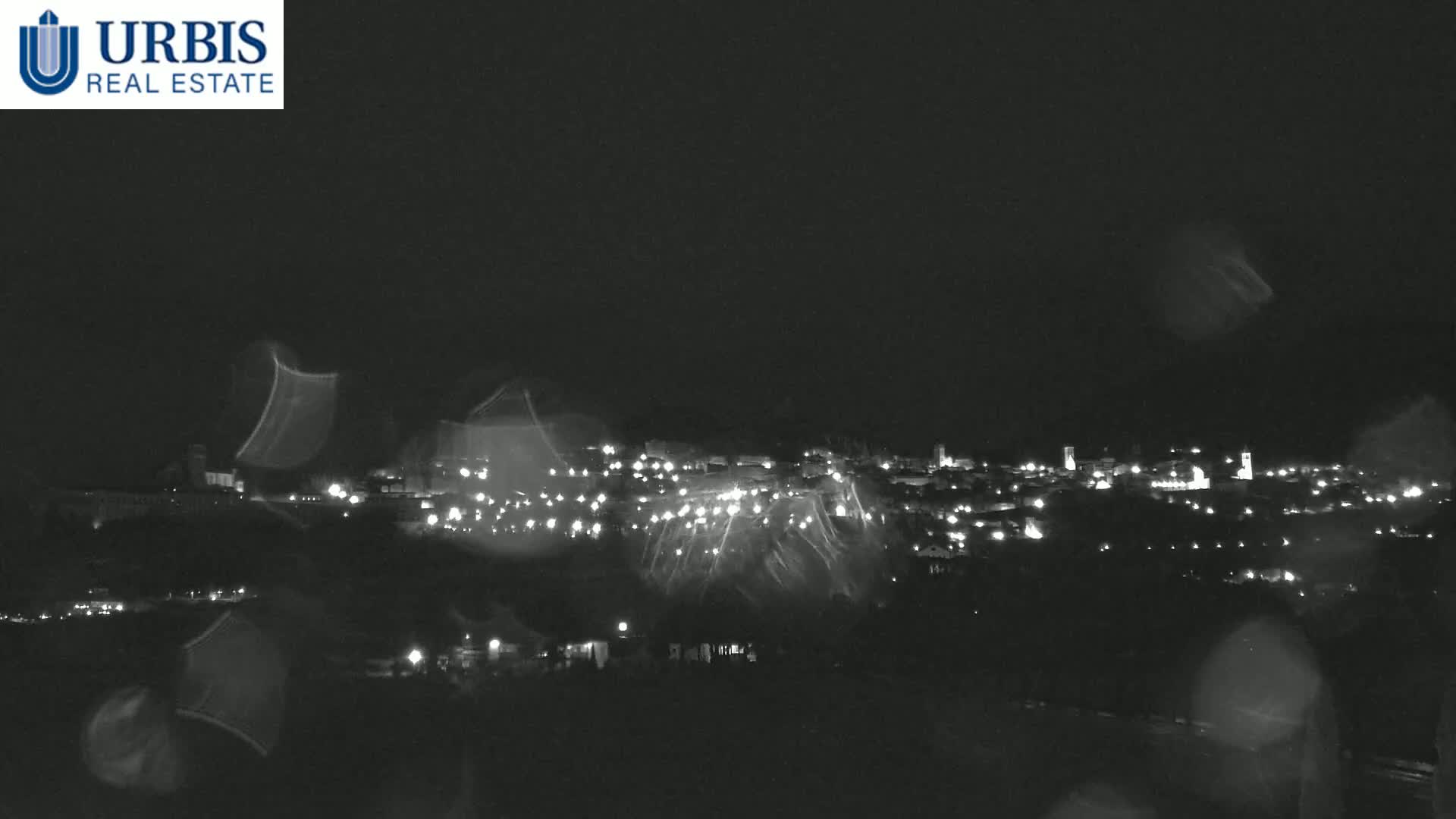 A nighttime view of a town's lights, seen through rain-streaked glass.