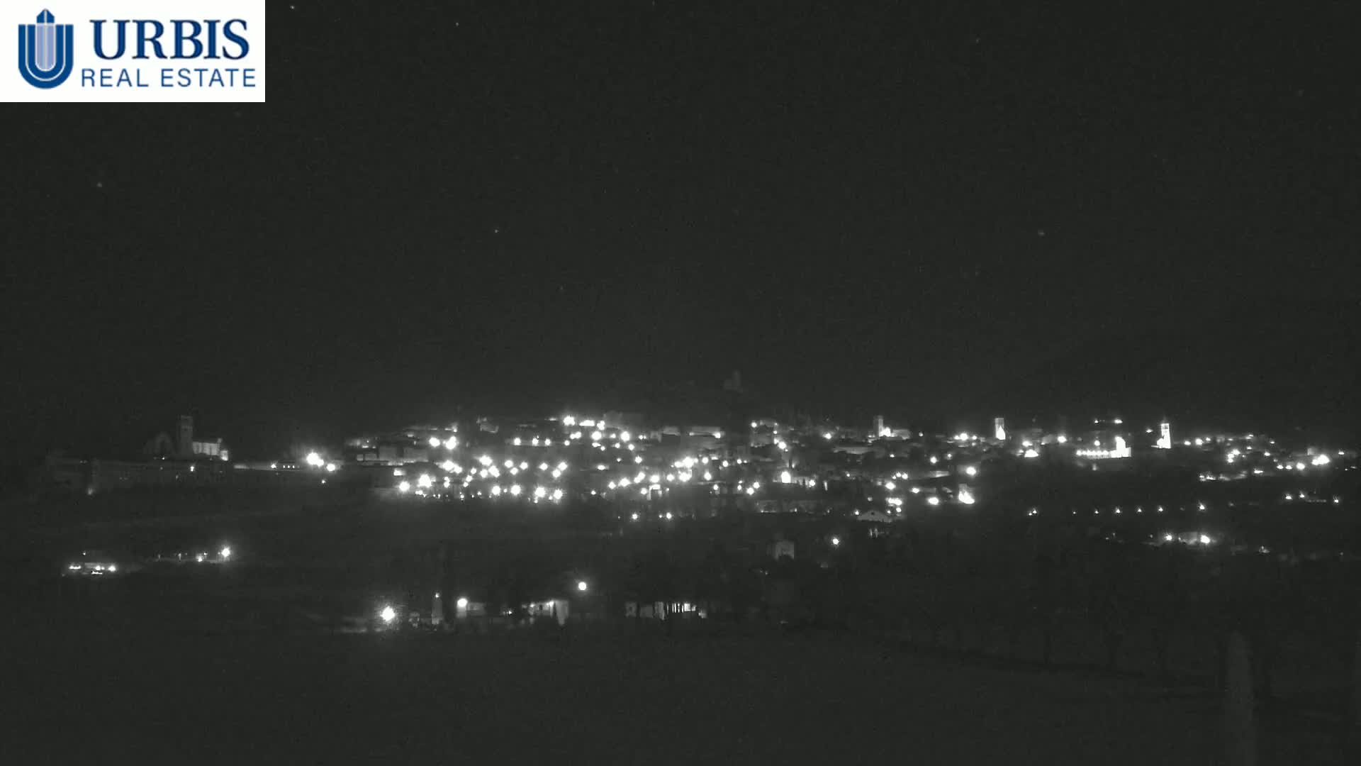 A nighttime long shot shows a small town illuminated by its lights under a clear, dark sky.