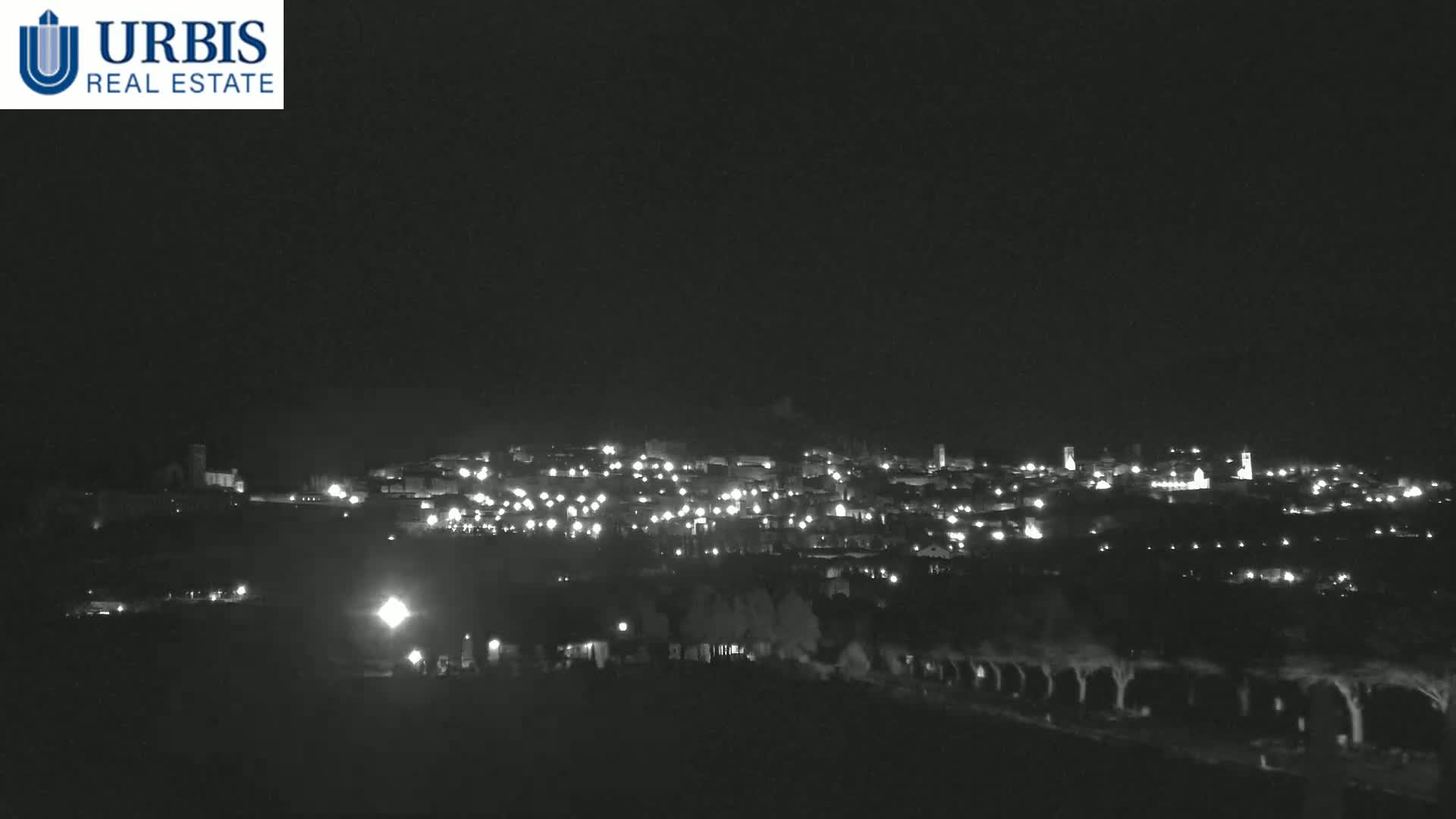 A nighttime, long-range view of a town illuminated by many lights, under a clear, dark sky.