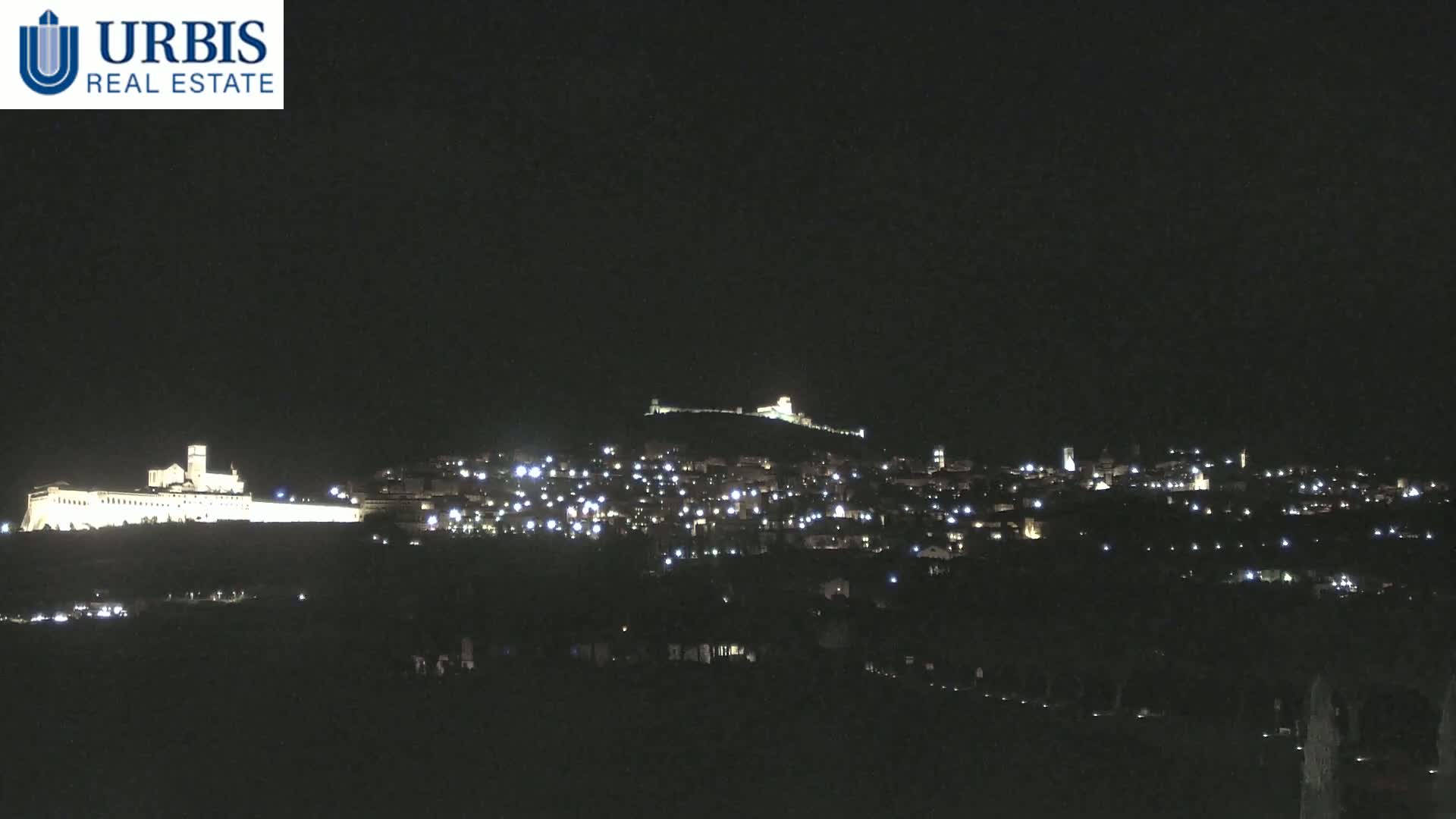 A nighttime view of a city and a large building complex illuminated against a dark sky.